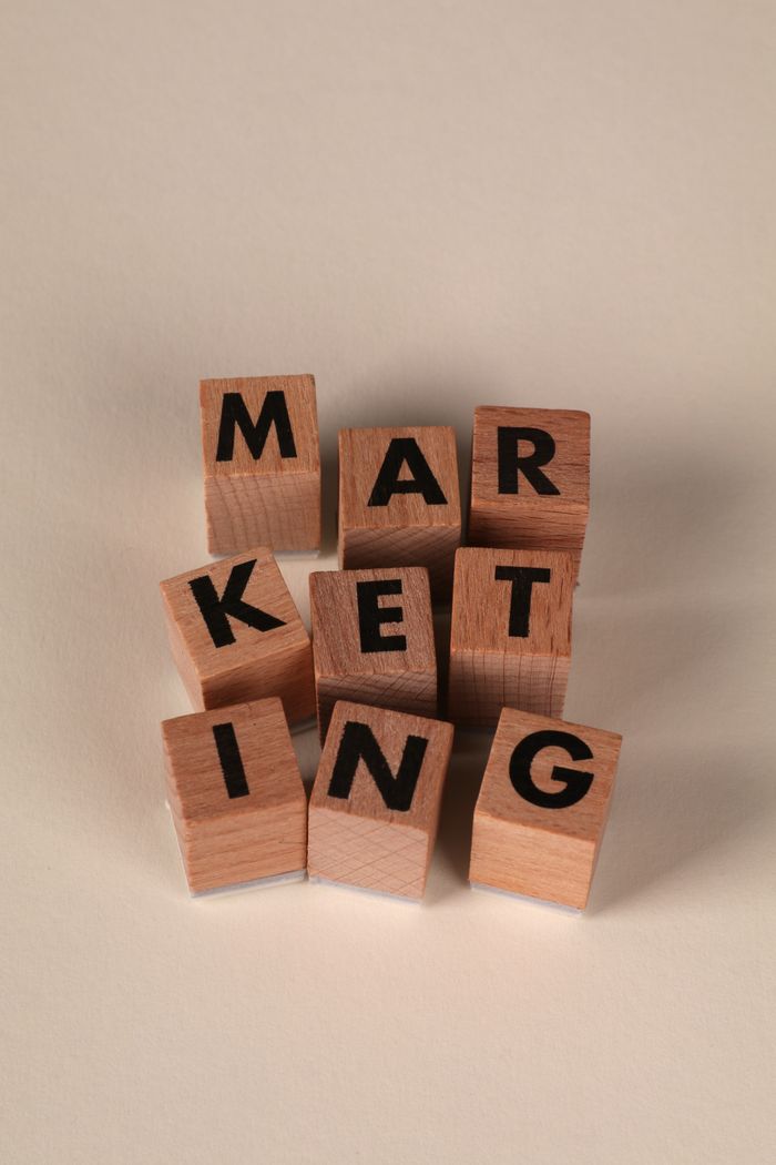 Wooden blocks arranged to spell MARKETING on a neutral background.